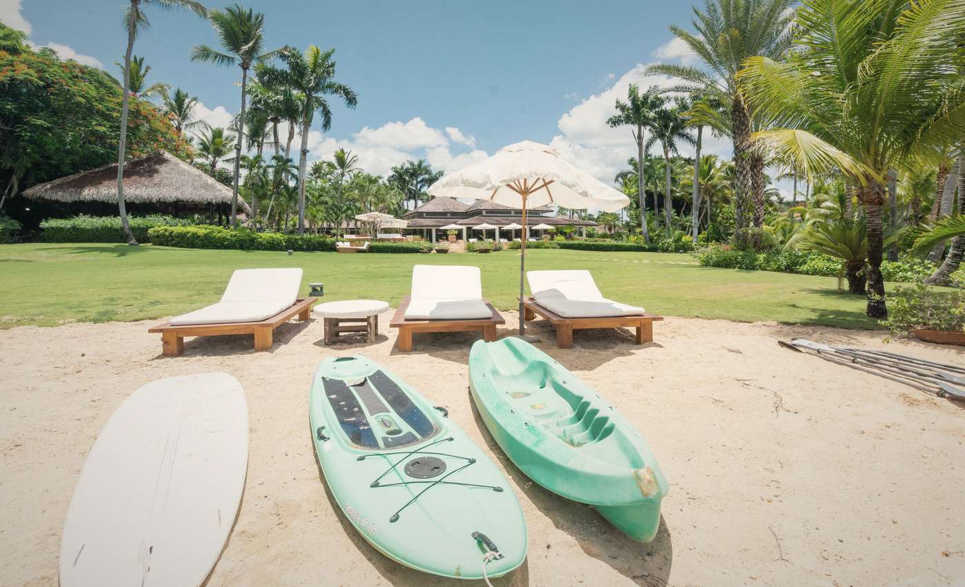Paddleboards and loungers on the sand in front of a house
