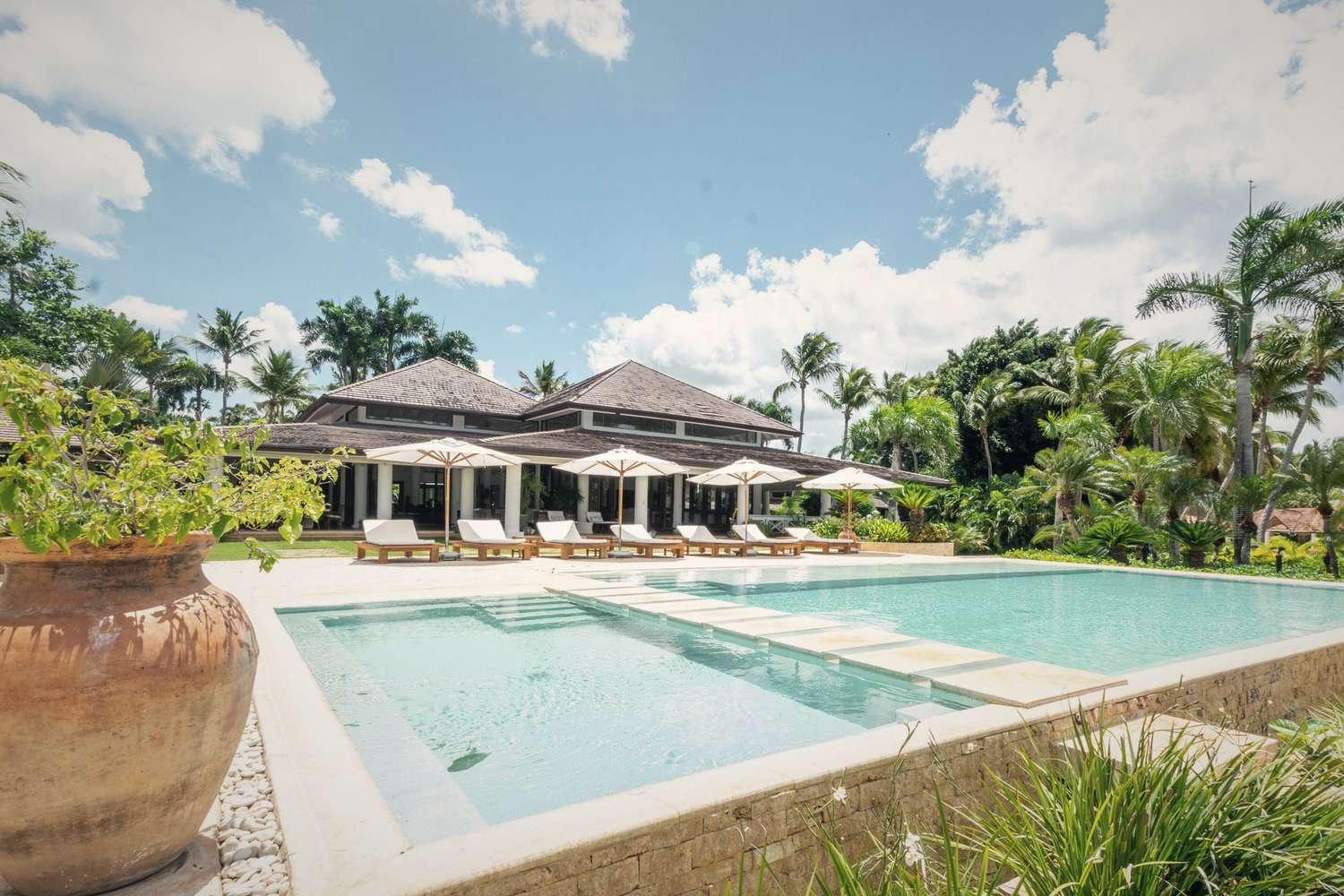 A villa and its pool, parasols open, in the late morning