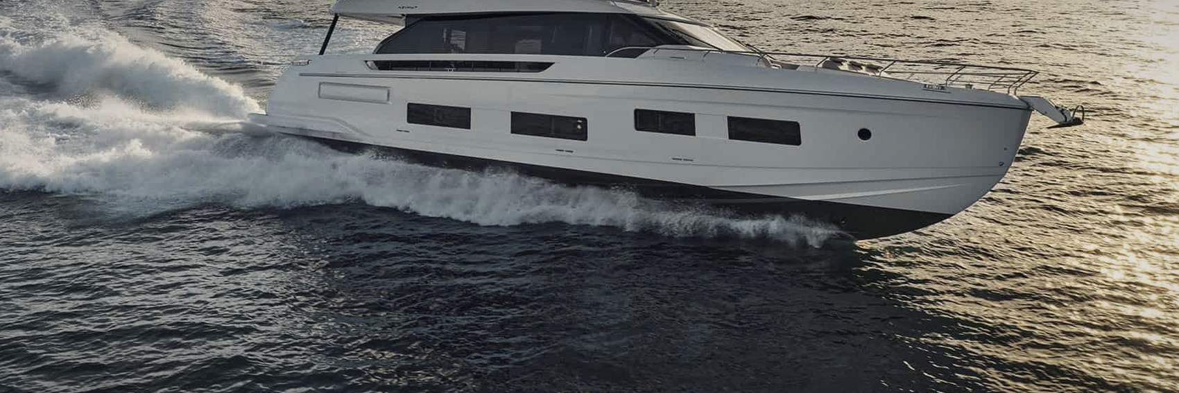 The hull and bow wave of a motor yacht under way in low light
